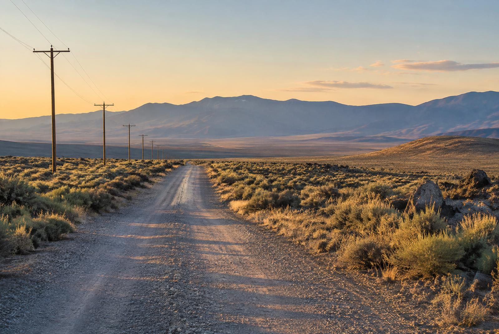 Gravel road crossing high desert sagebrush toward distant Northern Nevada mountains